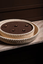 Beige Schalenkerze mit geriffeltem Rand, dunklem Wachs und fünf brennenden Dochten